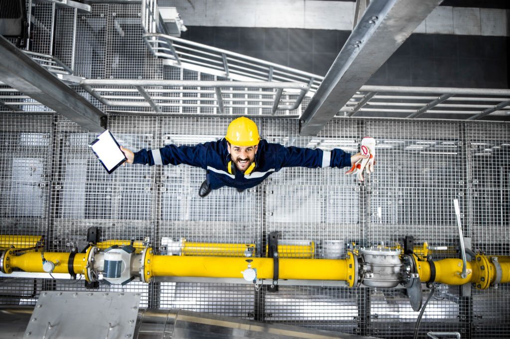 Top View Of Cheerful Refinery Worker Standing By Gas Pipe And Looking Up.